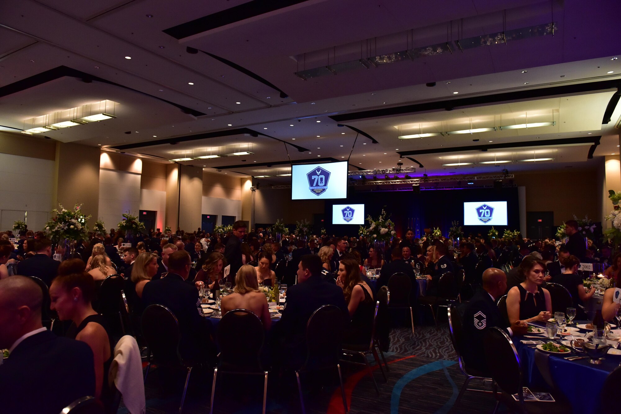 Tables of people sitting down in formal attire in a ballroom