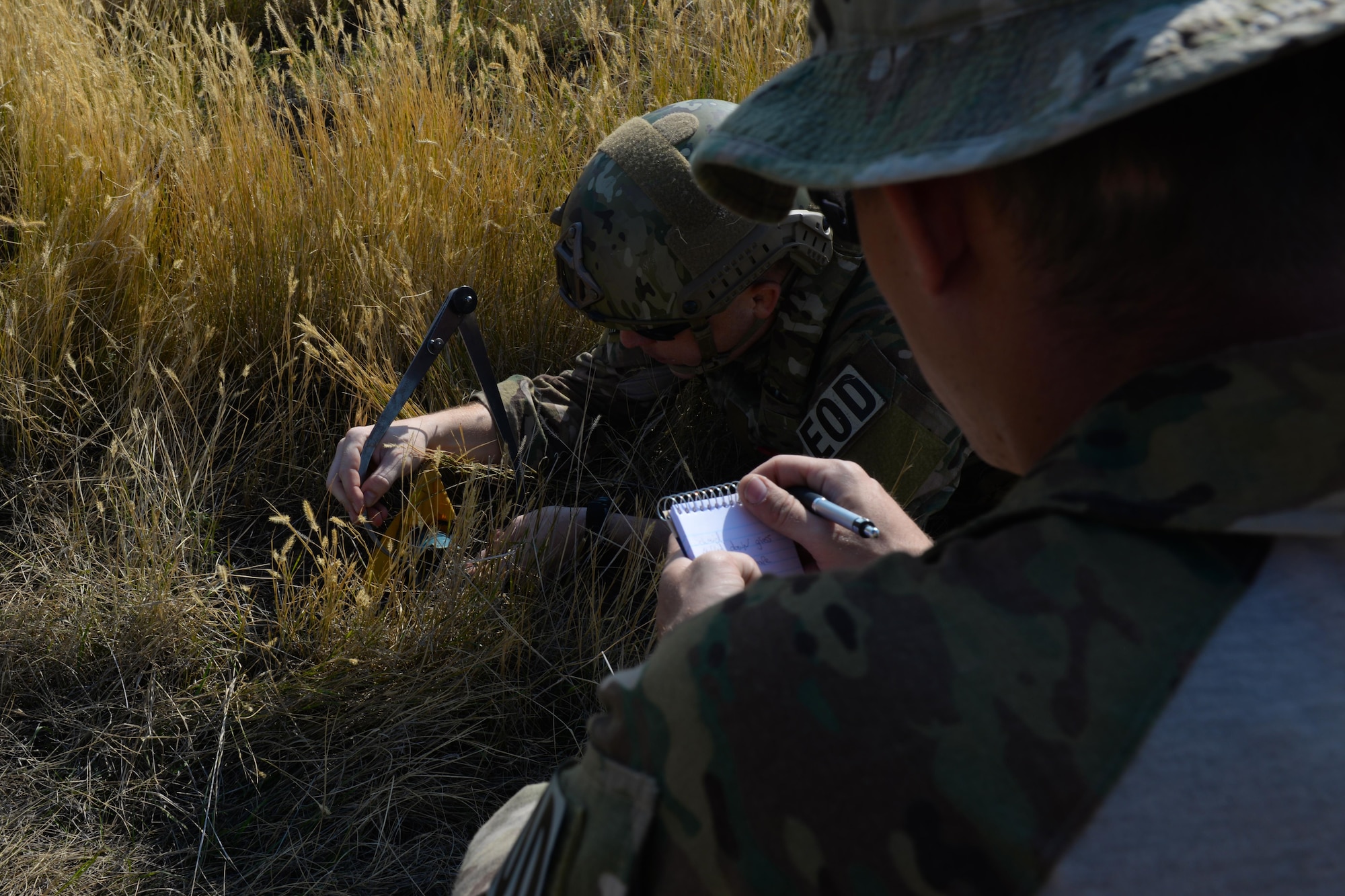 Senior Airman Zachary McCarthy, an explosive ordnance disposal technician assigned to the 28th Civil Engineer Squadron, takes notes on Staff Sgt. Robert Schmid, an EOD technician assigned to the 28th CES, while Schmid measures the dimensions of an unexploded ordnance during an EOD Team of the Year competition at Ellsworth Air Force Base, S.D., Sept. 12, 2017.  This scenario during the event had teams inspect different ordnances to determine the make and model of the explosives. (U.S. Air Force photo by Airman Nicolas Z. Erwin)