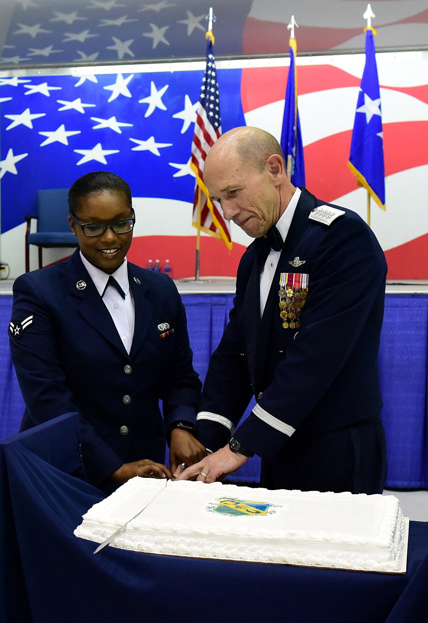 Gen. Mike Holmes, right, commander of Air Combat Command, and Airman 1st Class Deja Adams, left, 4th Logistics Readiness Squadron flight service center apprentice, cut a cake during the the 4th Fighter Wing 75th Anniversary Gala, Sept. 16, 2017, at Seymour Johnson Air Force Base, North Carolina. The cake cutting tradition calls for the oldest and youngest Airman present to use a saber to cut the cake together. (U.S. Air Force photo by Airman 1st Class Victoria Boyton)