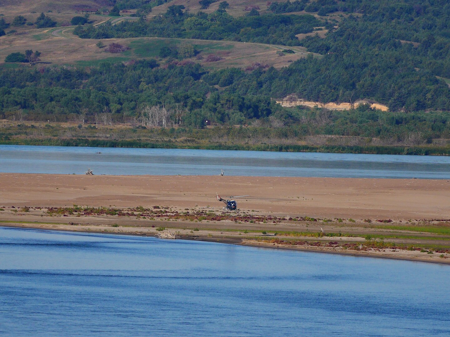 A helicopter flies low over a sandbar in the Missouri River.