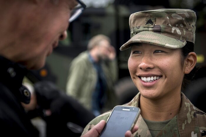 A service member speaks to a person holding a phone.