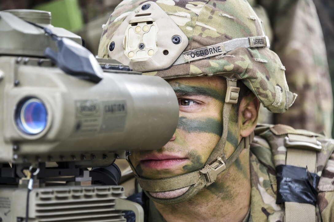 A soldier looks through a lens.