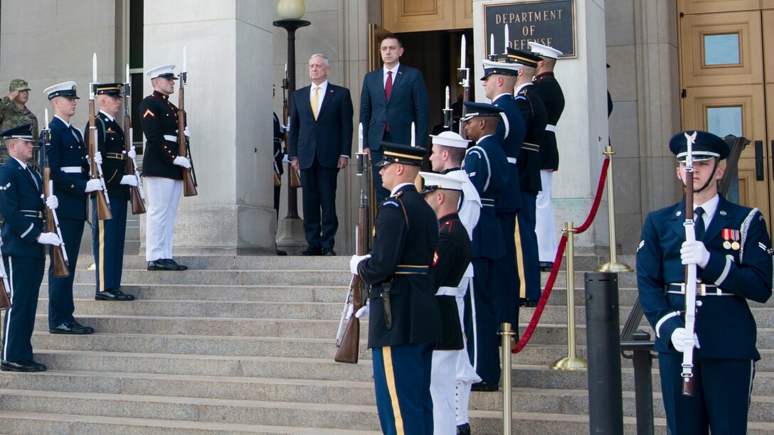 Defense Secretary Jim Mattis stands with Romania's defense minister on steps.
