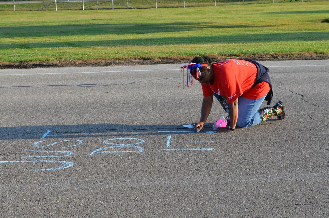Master Sgt. Cynthia Holland, 445th Operations Group NCO in charge of administration, writes an encouraging message near the 445th Airlift Wing hydration station to participants in the 2017 Air Force Marathon Sept. 16. (U.S. Air Force photo/Lt. Col. Cynthia Harris)