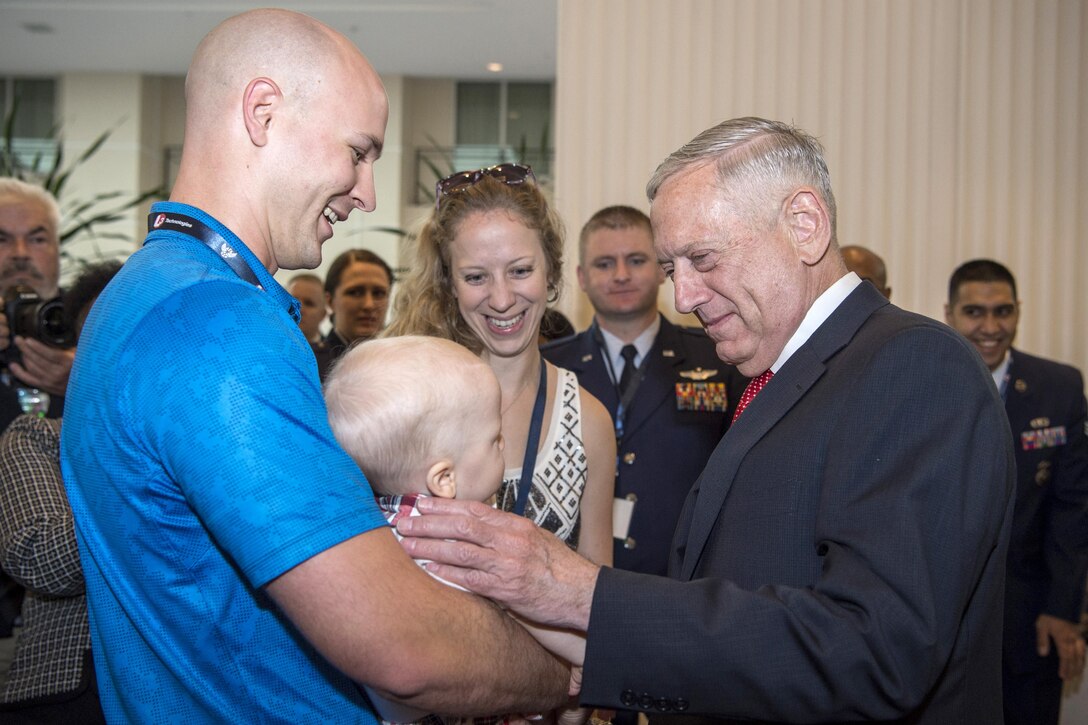 Defense Secretary Jim Mattis interacts with an infant held by a man.