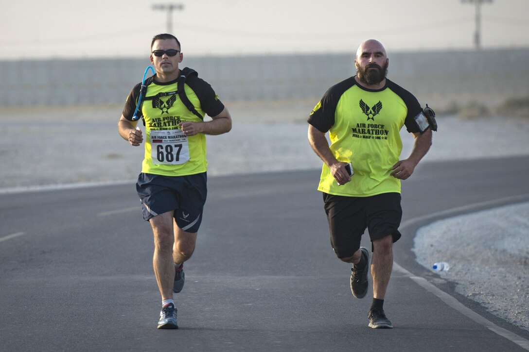 Two airmen run on a road.