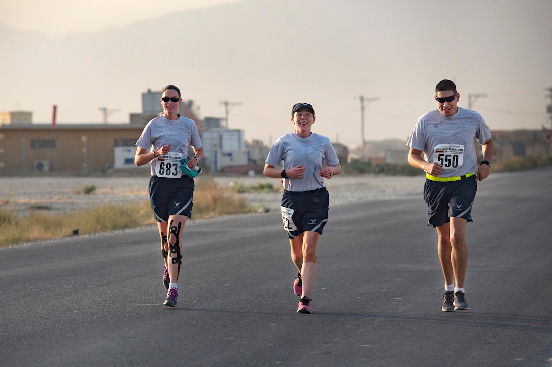 Three members of the Air Force run on a road.