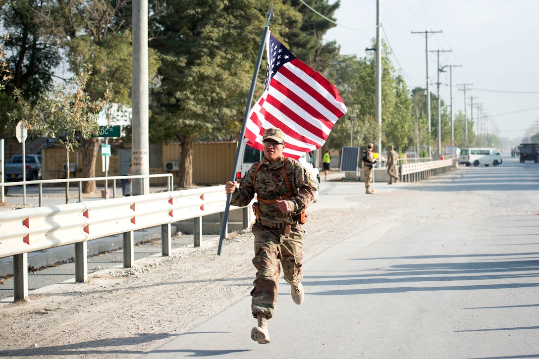 An airman carries an American flag while running.