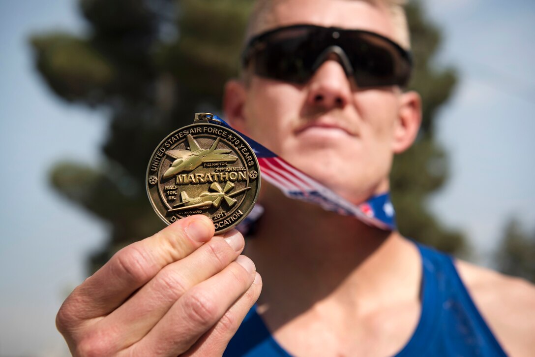An airman holds up a medal hanging around his neck.