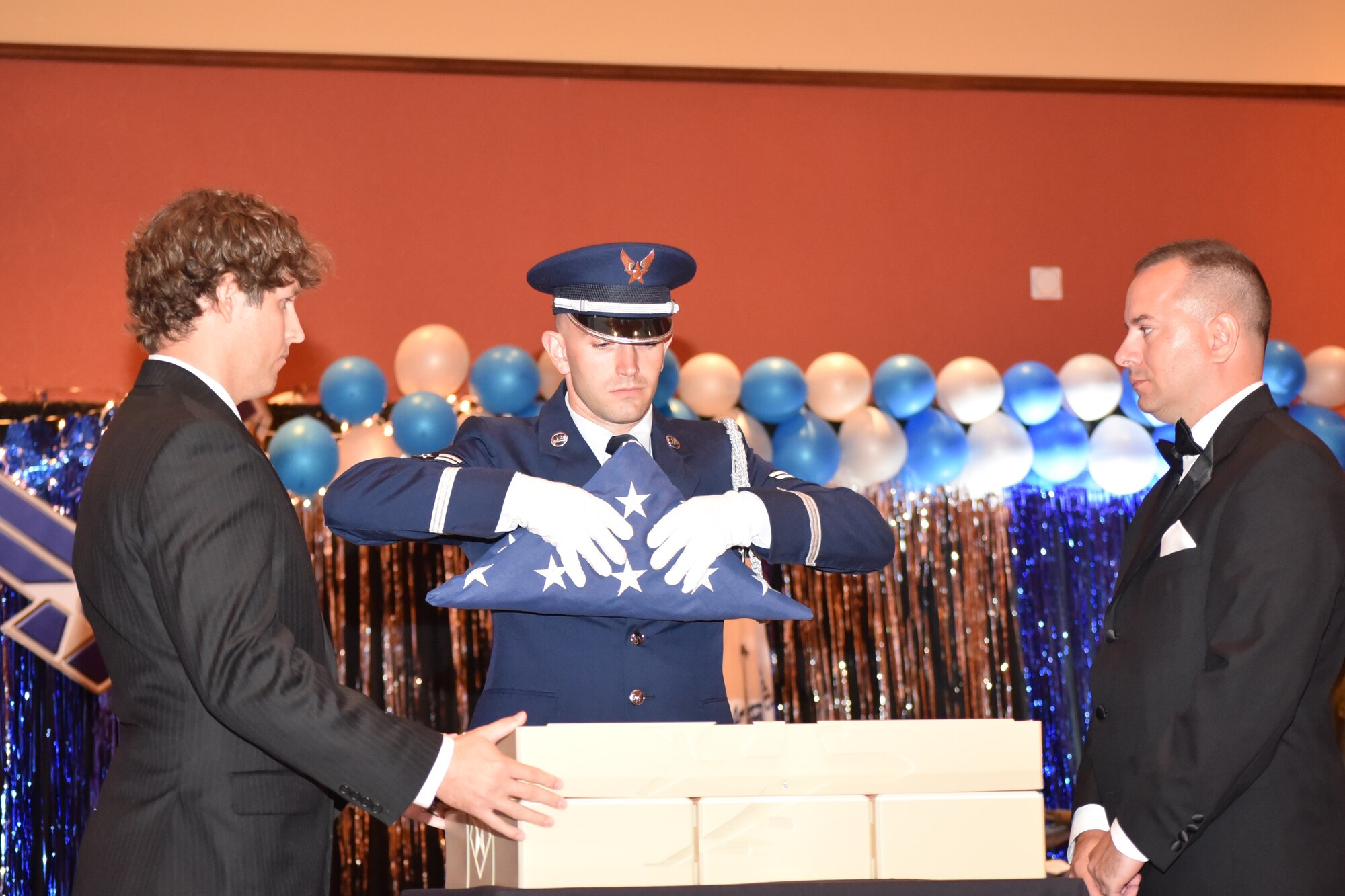 During the Air Force Ball on Sept. 16, Todd Bayles, mechanical engineer from the 76th Commodities Maintenance Group's REACT office, and Jerry Bryza, media chief with the 72nd Air Base Wing Public Affairs office, stood by as Honor Guard member Airman 1st Class Joshua Stuff placed the last flag to fly over Bldg. 460 into the 75th anniversary time capsule.