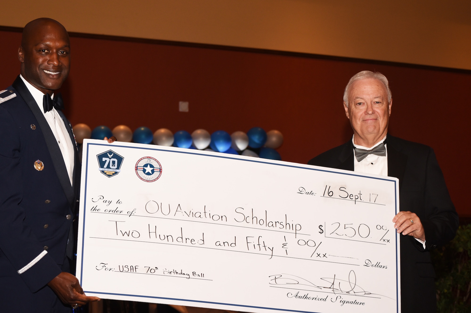 Col. Kenyon Bell, 72nd Air Base Wing commander, presents Garry Richey, former Oklahoma City Air Logistics Center executive director, with a $250 check for the OU Aviation Scholarship as a 'thank you' for being the guest speaker of this year's Air Force Ball on Sept. 16.