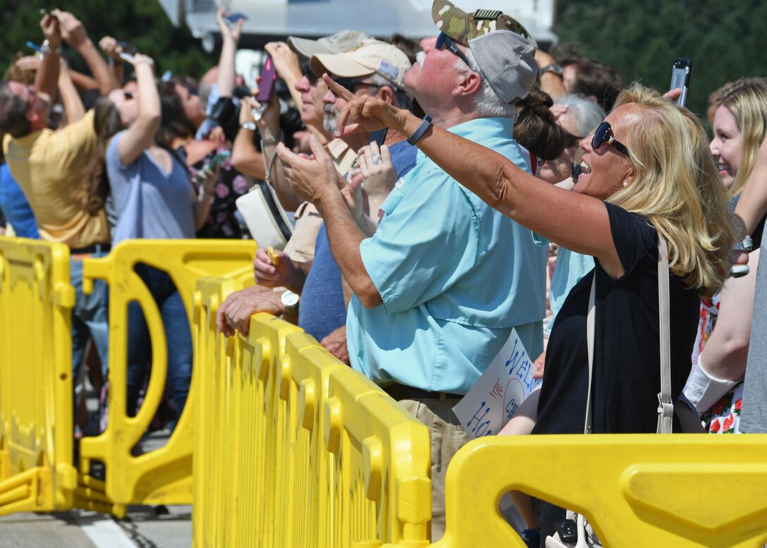 Families and friends of returning deployers point up as five C-130H3 Hercules pass overhead at Dobbins Air Reserve Base, Ga, Sept. 18, 2017. The group of loved ones gathered outside on the flightline to welcome home the returning members from their deployment. (U.S. Air Force photo by Staff Sgt. Miles Wilson)