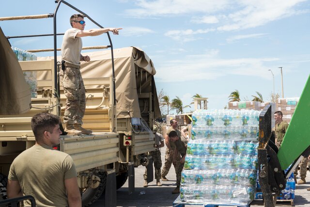 Guardsmen move pallets of water.
