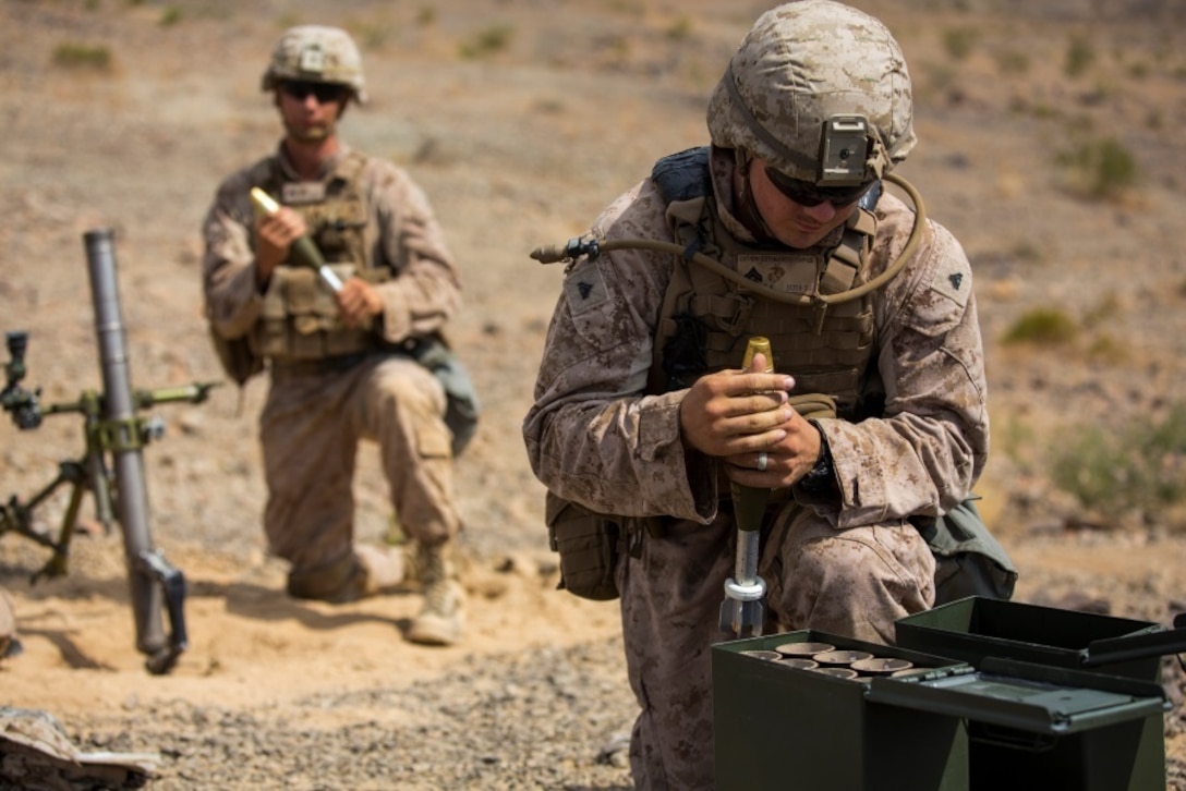 Cpl. Christopher Stephens, mortarman, 1st Battalion, 1st Marine Regiment, prepares rounds for Pfc. Thomas Curtis, mortarman, 1/1, during an individual training exercise at Range 410A aboard the Marine Corps Air Ground Combat Center, Twentynine Palms, Calif., July 25, 2017. 1/1 is based out of Marine Corps Base Camp Pendleton, Calif. and is serving as part of the GCE during ITX 5-17.  (U.S. Marine Corps photo by Pfc. Margaret Gale)