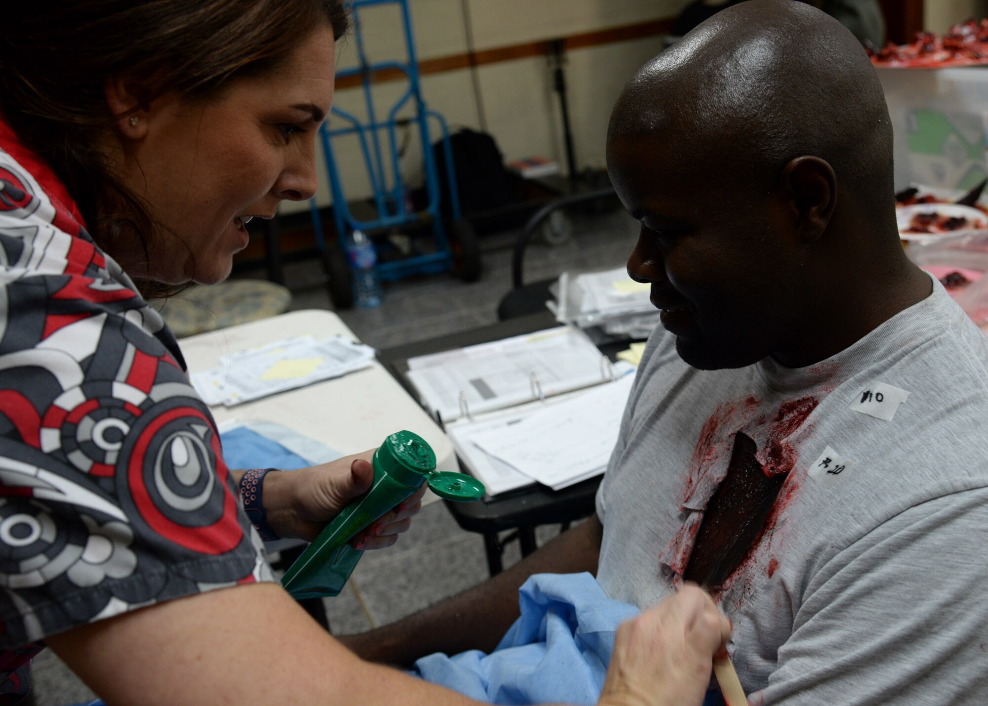 Jamie Gujski, left, 51st Medical Group simulation operator, applies moulage onto Staff Sgt. Dennis Middleton, 51st Communication Squadron project manager, before the start of a simulated building fire during exercise Beverly Herd 17-3 at Osan Air Base, Republic of Korea September 20, 2017. Gujski makes the mock injuries by hand and gives medical personnel the chance to provide realistic care to patients to test how well they treat casualties during an emergency. (U.S. Air Force photo by Tech Sgt. Ashley Tyler)