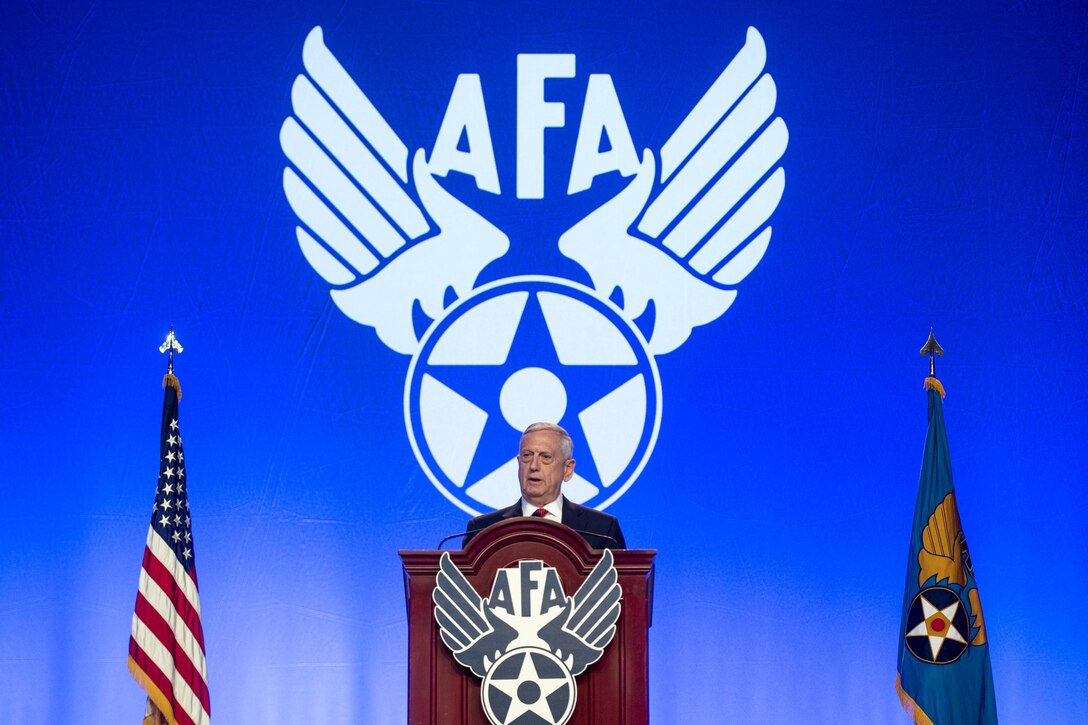 Defense Secretary Jim Mattis speaks from a podium to people in a conference hall.
