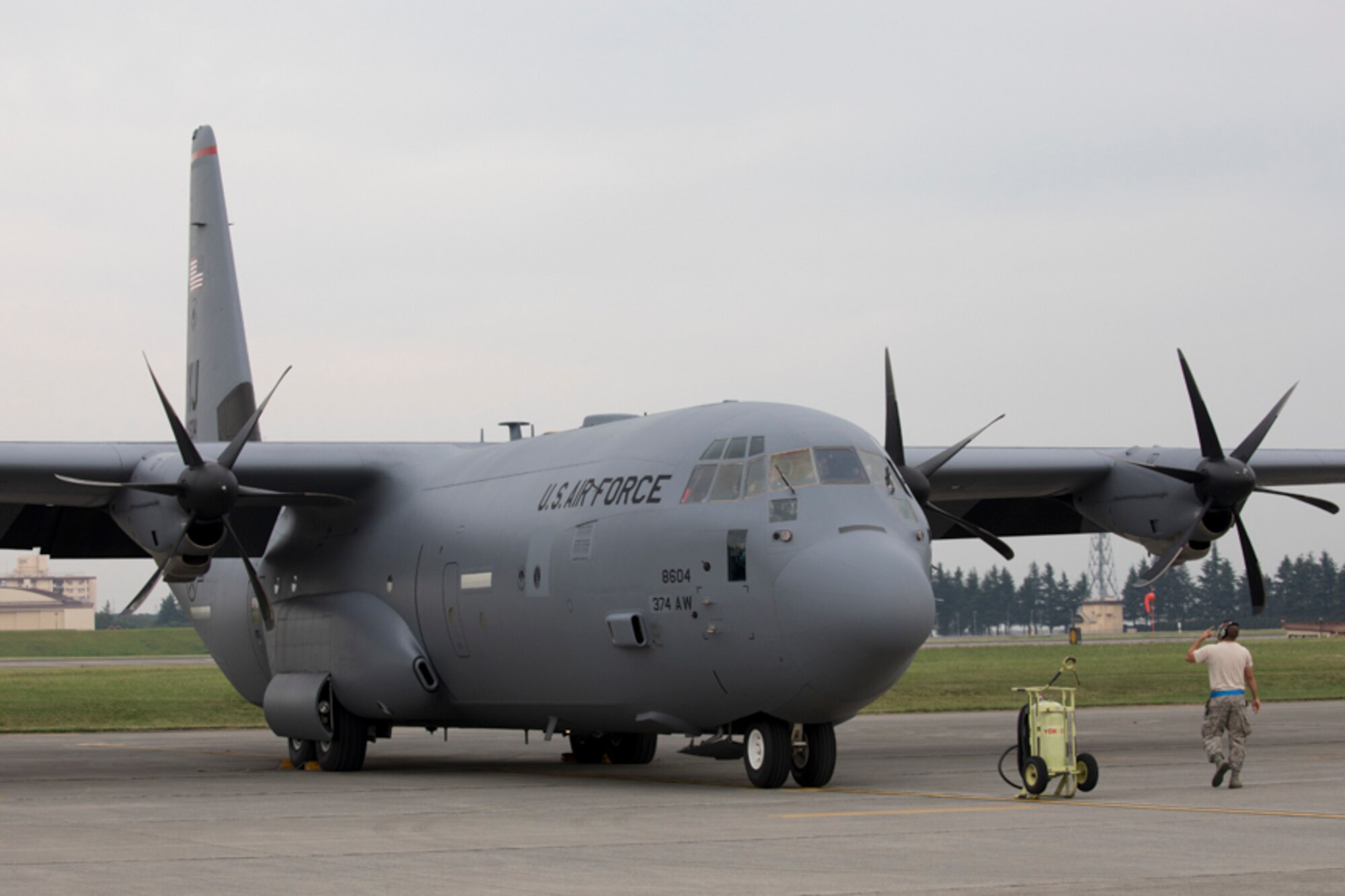 A crew chief from the 374th Aircraft Maintenance Squadron marshals a C-130J Super Hercules at Yokota