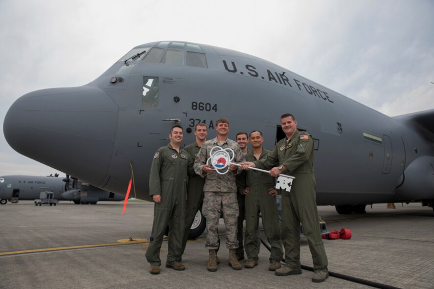 Members of the C-130J delivery team pose for a photo in front of a C-130J Super Hercules at Yokota