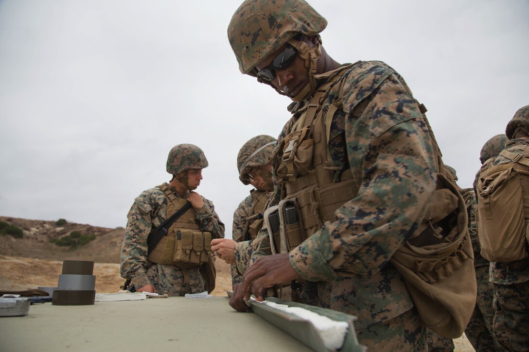 A Marine stands at a table working.