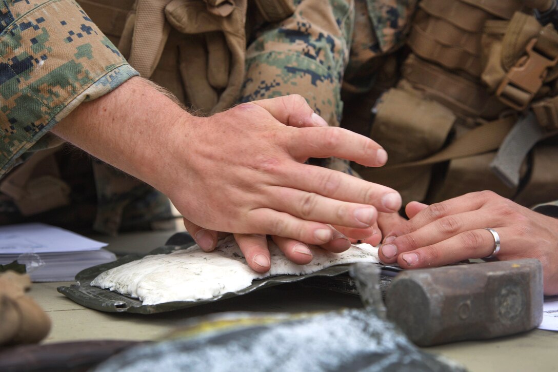 Marines hands press down on a white substance.