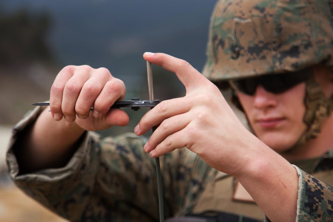 A Marine uses pliers on on a blasting cap.