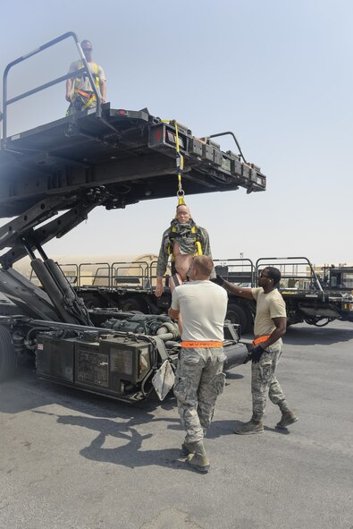 U.S. Air Force Senior Airmen Russell Robinson, center, and Columbus Johnson, right, attempt to stabilize a training dummy moments after Tech. Sgt. David Kitchen pushed the training dummy from a 60K Tunner cargo loader during a fall protection exercise at Al Udeid Air Base, Qatar, Sept. 8, 2017.
