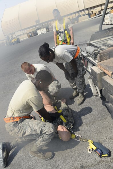 U.S. Air Force Senior Airman Columbus Johnson, foreground, simulates chest compressions on a training dummy while Senior Airmen Russell Robinson, kneeling, Latreshia Peterson, hands on her knees, and Tech. Sgt. David Kitchen, background, look on during a fall protection exercise at Al Udeid Air Base, Qatar, Sept. 8, 2017.