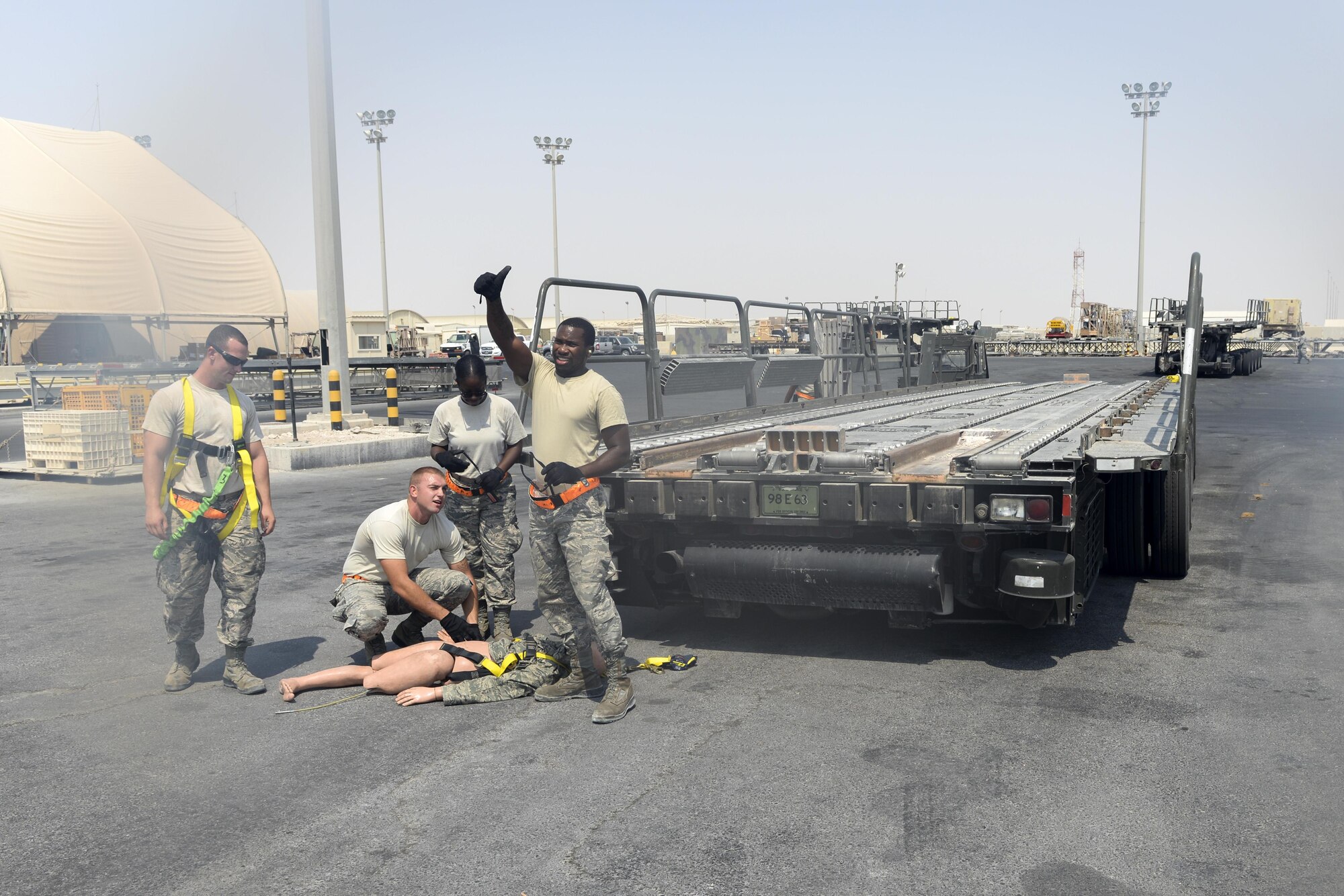 U.S. Air Force Senior Airman Columbus Johnson gives a thumbs up while Senior Airmen Russell Robinson, kneeling, Latreshia Peterson, background, and Tech. Sgt. David Kitchen, left, look on during a fall protection exercise at Al Udeid Air Base, Qatar, Sept. 8, 2017.