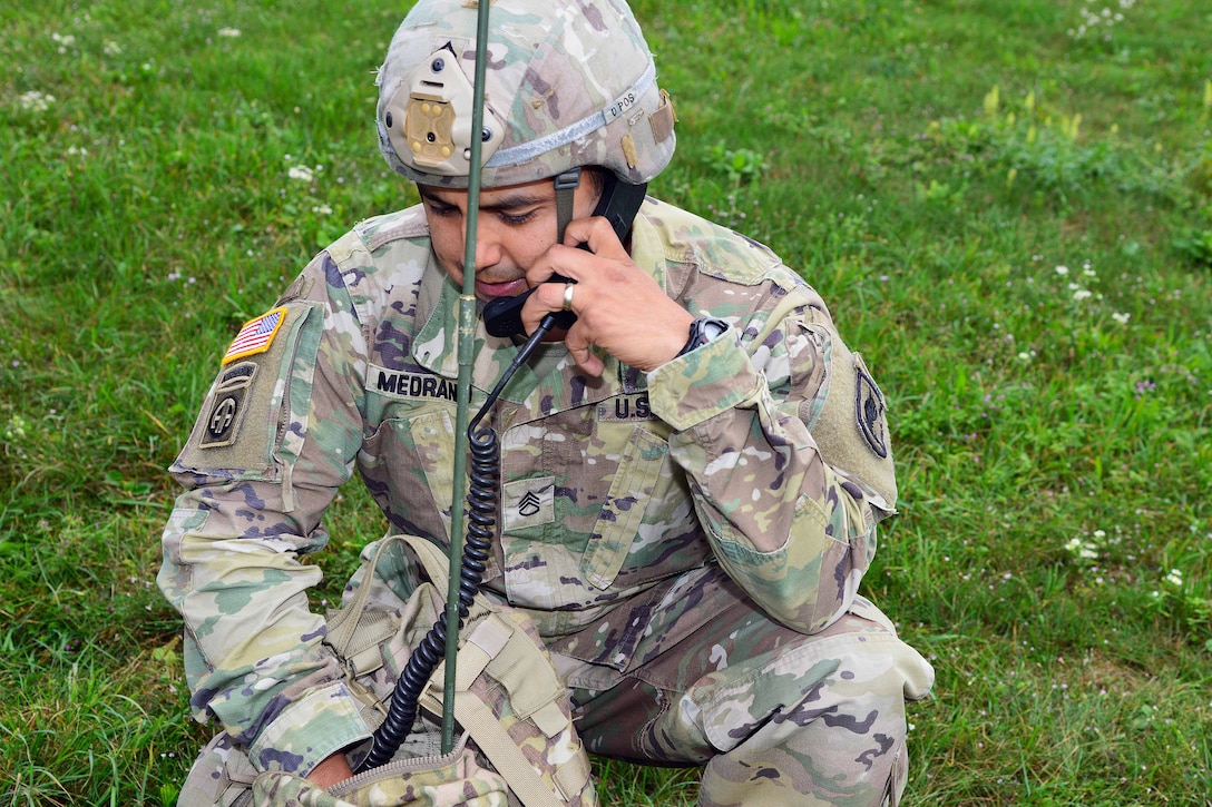A soldier uses a radio held in a bag.
