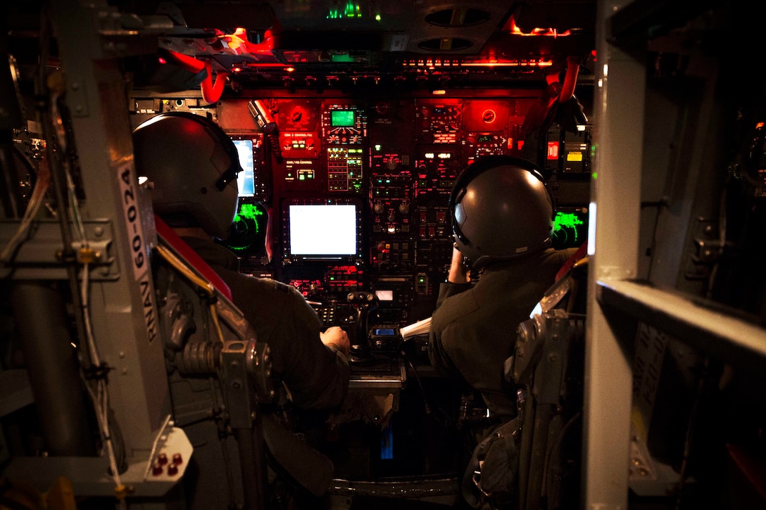 Two airmen sit in the lower deck of an aircraft.