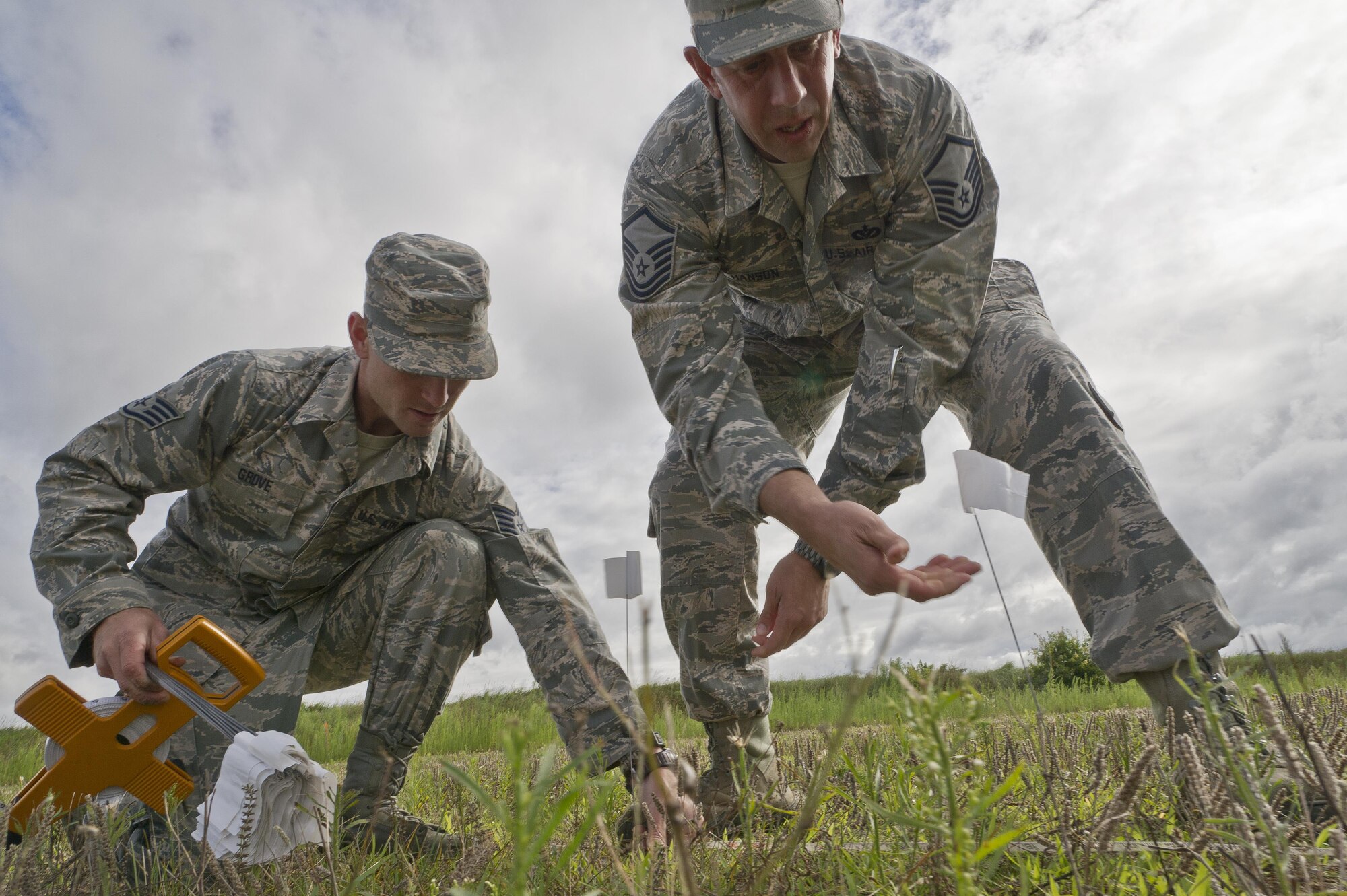 U.S. Air Force Staff Sgt. Brandon Grove, left, and Master Sgt. Jason Hanson, both assigned to the 302nd Civil Engineer Squadron, Peterson AFB, Colo., place suvey flags for a bare base setup at Young Air Assault Strip, Fort McCoy, Wis., Aug. 4, 2017, during exercise Patriot Warrior.