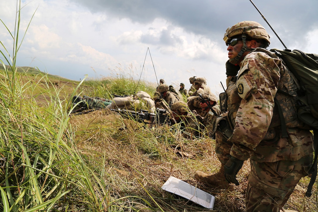 A soldier maintains radio contact while operating as a range safety for a support by fire position of M240 machine guns.