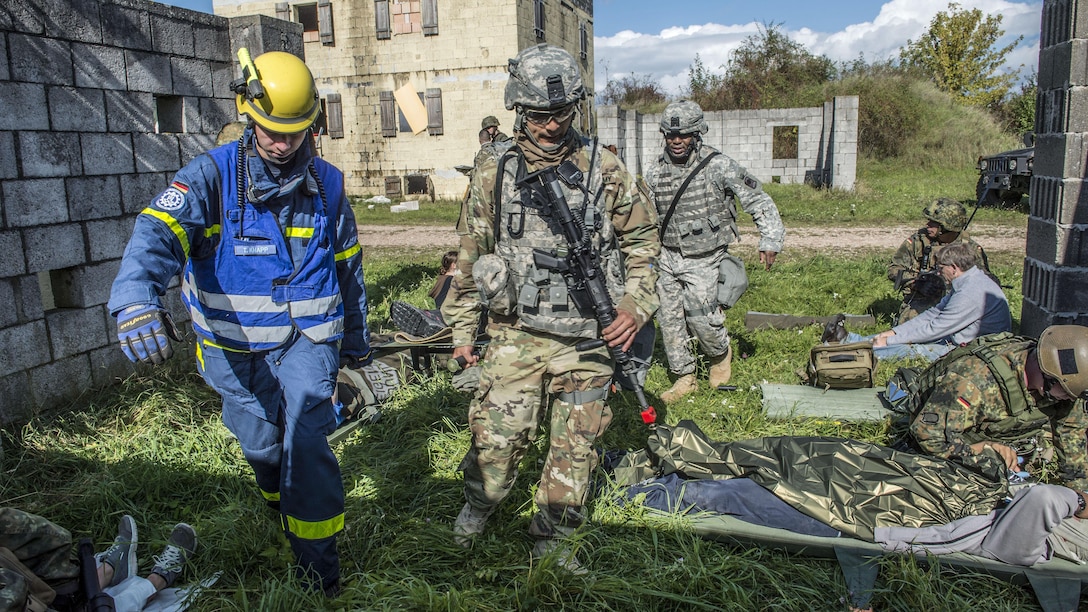 Personnel carry a stretcher as role players lie on the ground nearby.