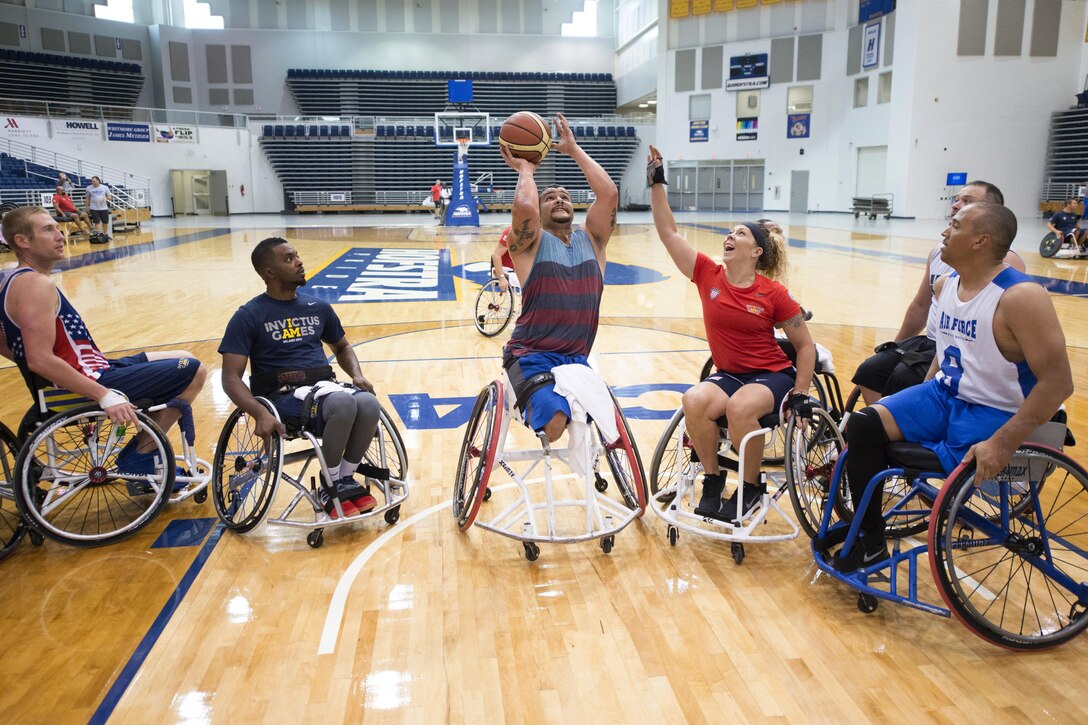 A row of people in wheelchairs play basketball.