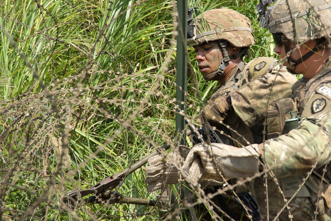 A soldier cuts through a concertina wire obstacle during a live-fire training event.
