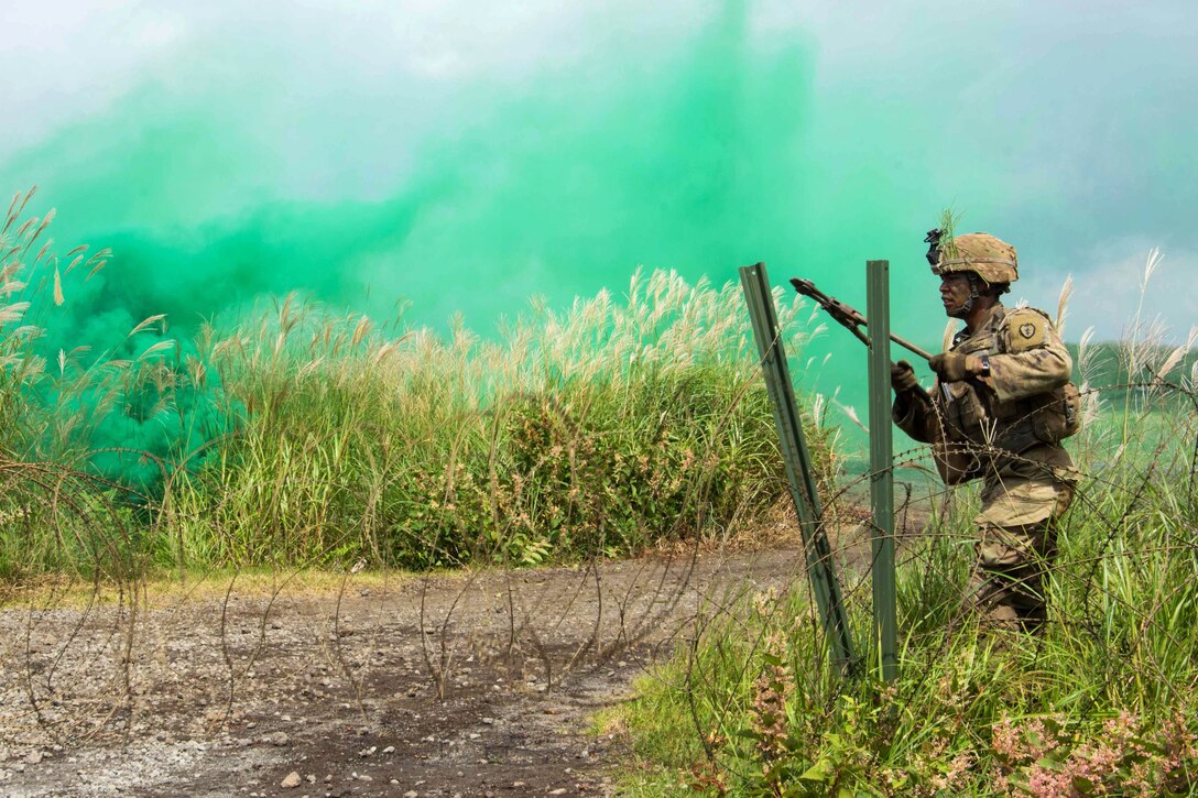 A soldier cuts through a concertina wire obstacle during a live-fire training event.