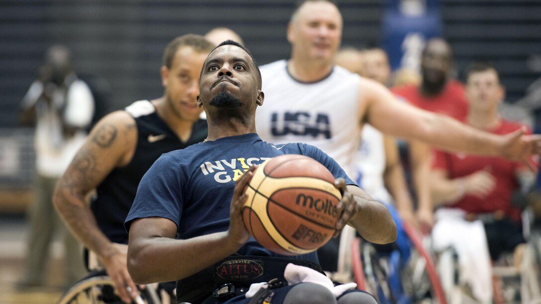 An athlete in a wheelchair holds up a basketball before throwing it.