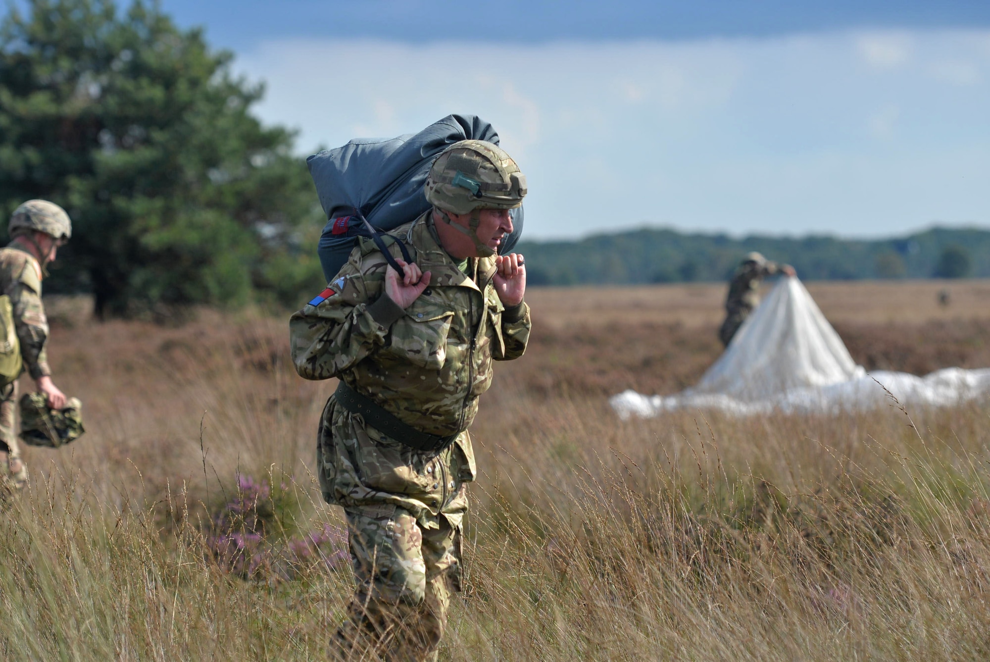 Paratroopers gather their belongings after successfully landing on the drop zone during exercise Falcon Leap Sept. 15, 2017, at the Houtdorperveld Drop Zone, Netherlands. Approximately 750 paratroopers from eight different countries participated in exercise Falcon Leap and the commemoration of Operation Market Garden. (U.S. Air Force photo by Airman 1st Class Codie Collins)