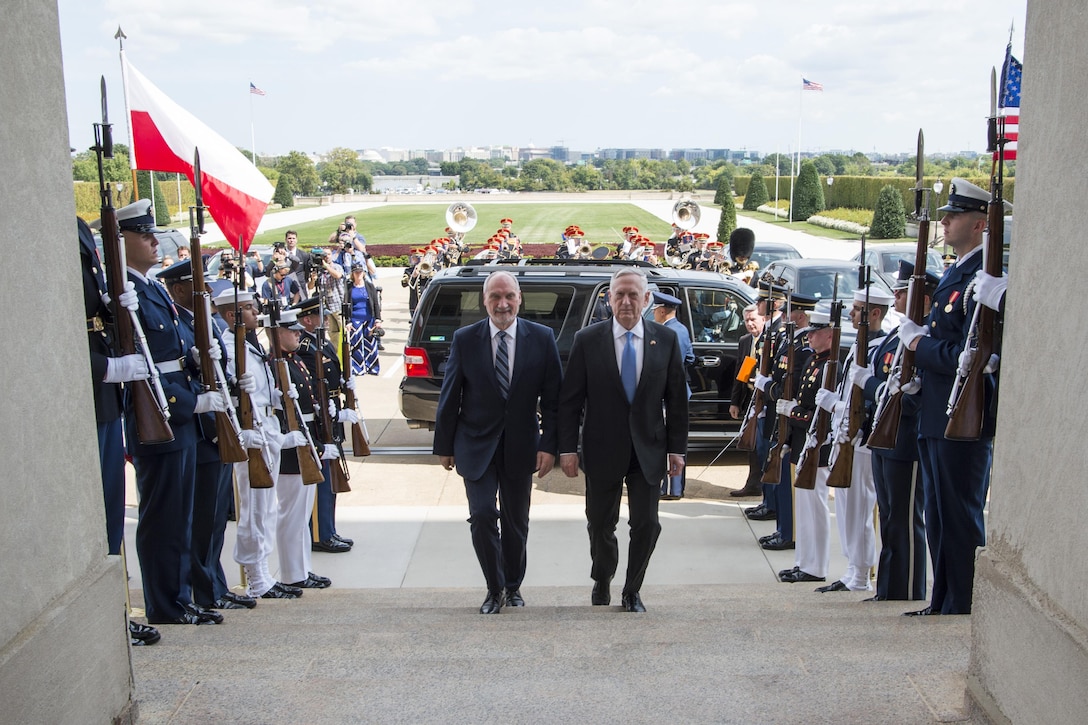 Defense Secretary Jim Mattis walks with another man up steps leading into the Pentagon.