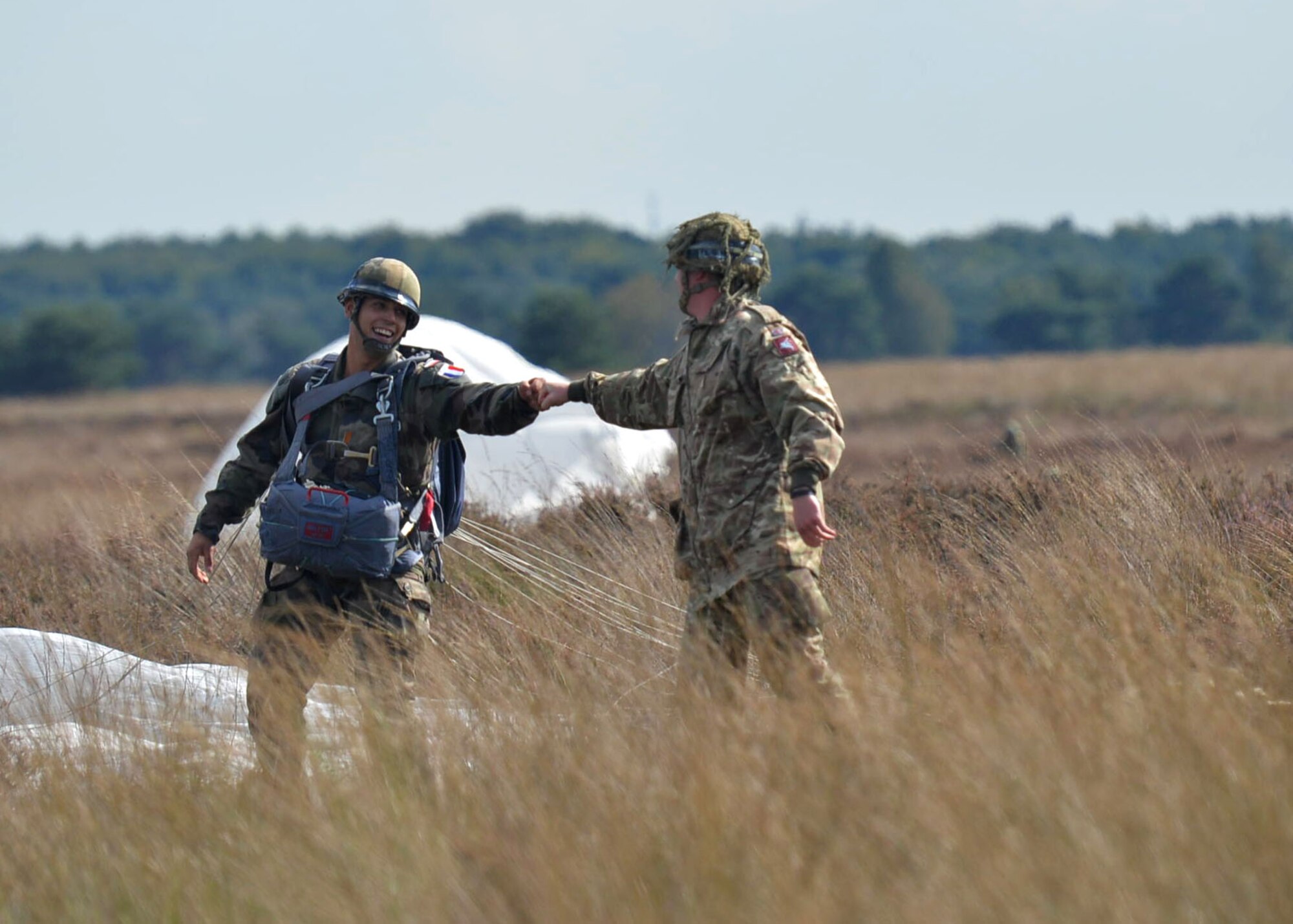 French and British paratroopers congratulate each other after successfully landing on the drop zone during exercise Falcon Leap Sept. 15, 2017, at the Houtdorperveld Drop Zone, Netherlands. Approximately 750 paratroopers from eight different countries participated in exercise Falcon Leap and the commemoration of Operation Market Garden. (U.S. Air Force photo by Airman 1st Class Codie Collins)