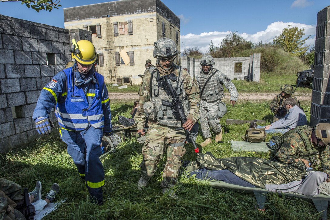 Personnel carry a stretcher as role players lie on the ground nearby.