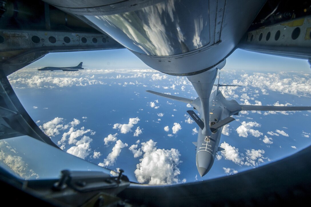 An aircraft boom extends to another aircraft in a cloudy blue sky.