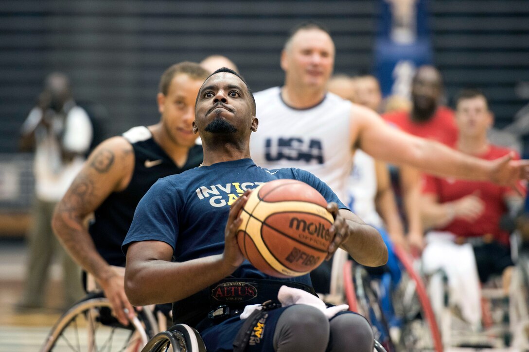 An athlete in a wheelchair holds up a basketball before throwing it.