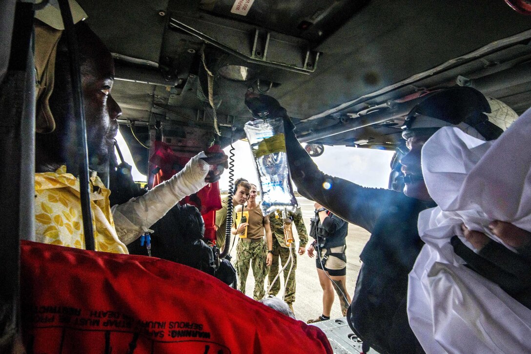 A sailor prepares a patient for evacuation in a helicopter.
