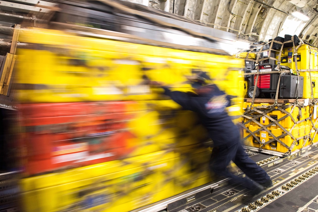 Two men unload cargo from the rear of an aircraft.