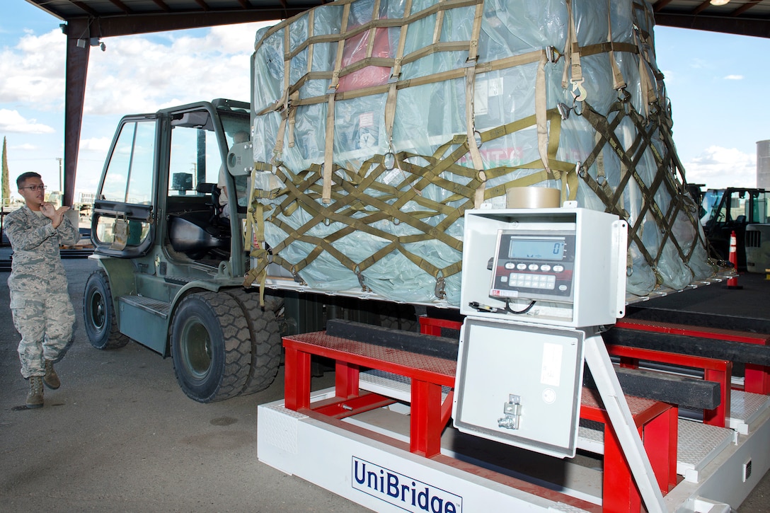 An airman guides another airmen operating a forklift.