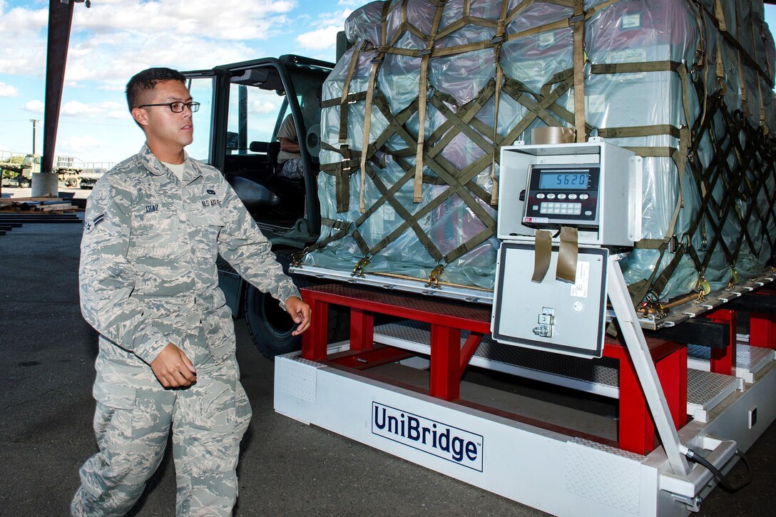 An airman weighs a pallet of equipment.