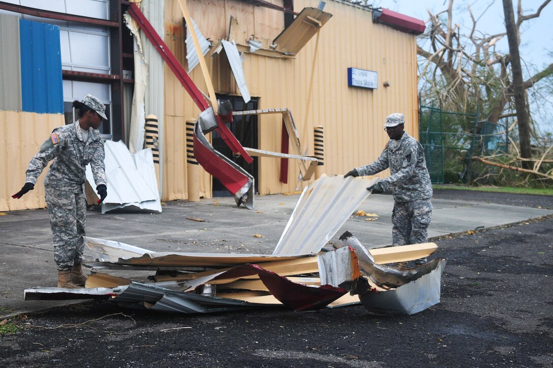 Two soldiers pile up building debris.