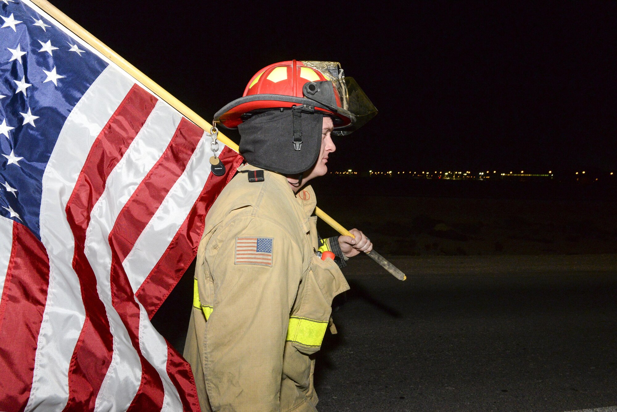 U.S. Air Force Staff Sgt. Austin Aldrich, firefighter assigned to the 379th Expeditionary Civil Engineering Squadron, caries a U.S. flag during an evening 9/11 memorial walk at Al Udeid Air Base, Qatar, Sept. 11, 2017.