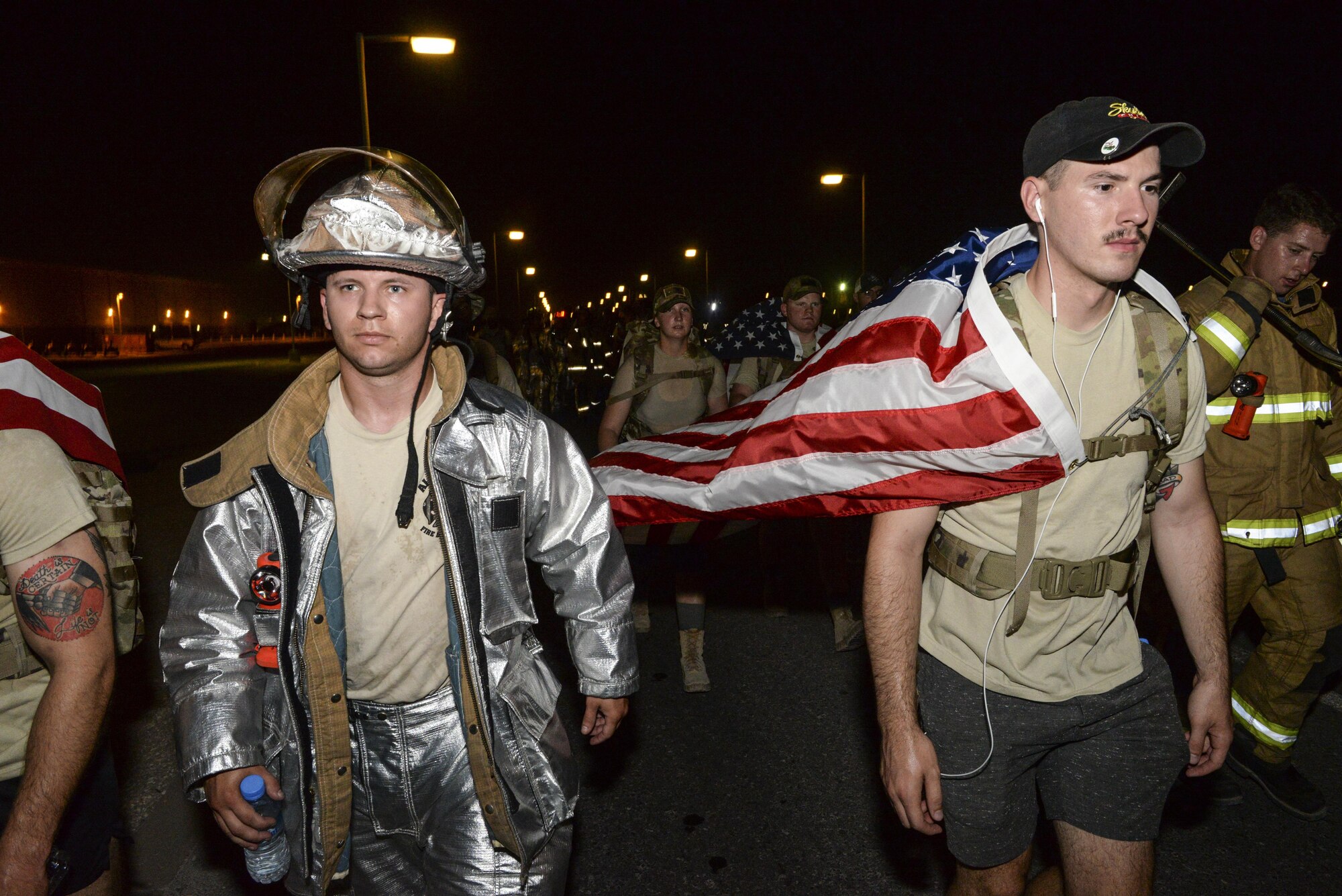 U.S. Air Force Senior Airmen Tyler Fisher, left, and Creed Heidkamp, firefighters assigned to the 379th Expeditionary Civil Engineering Squadron, participate in an evening 9/11 memorial walk at Al Udeid Air Base, Qatar, Sept. 11, 2017.